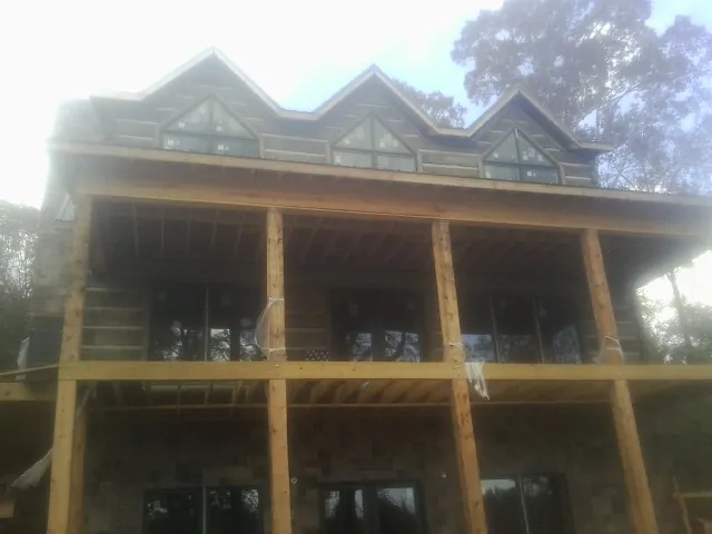 Dormers and porch framing on a large log home under construction — Roof Coating work by our crew in Mandan