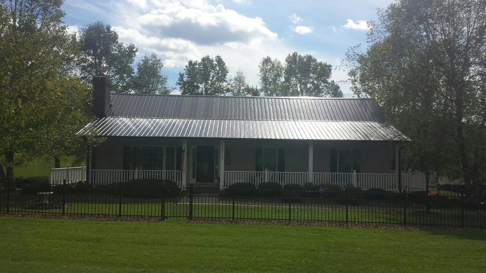 Gray metal roof on a brick ranch with a full width front porch — Gutter Guard Installation work by our crew in Mandan