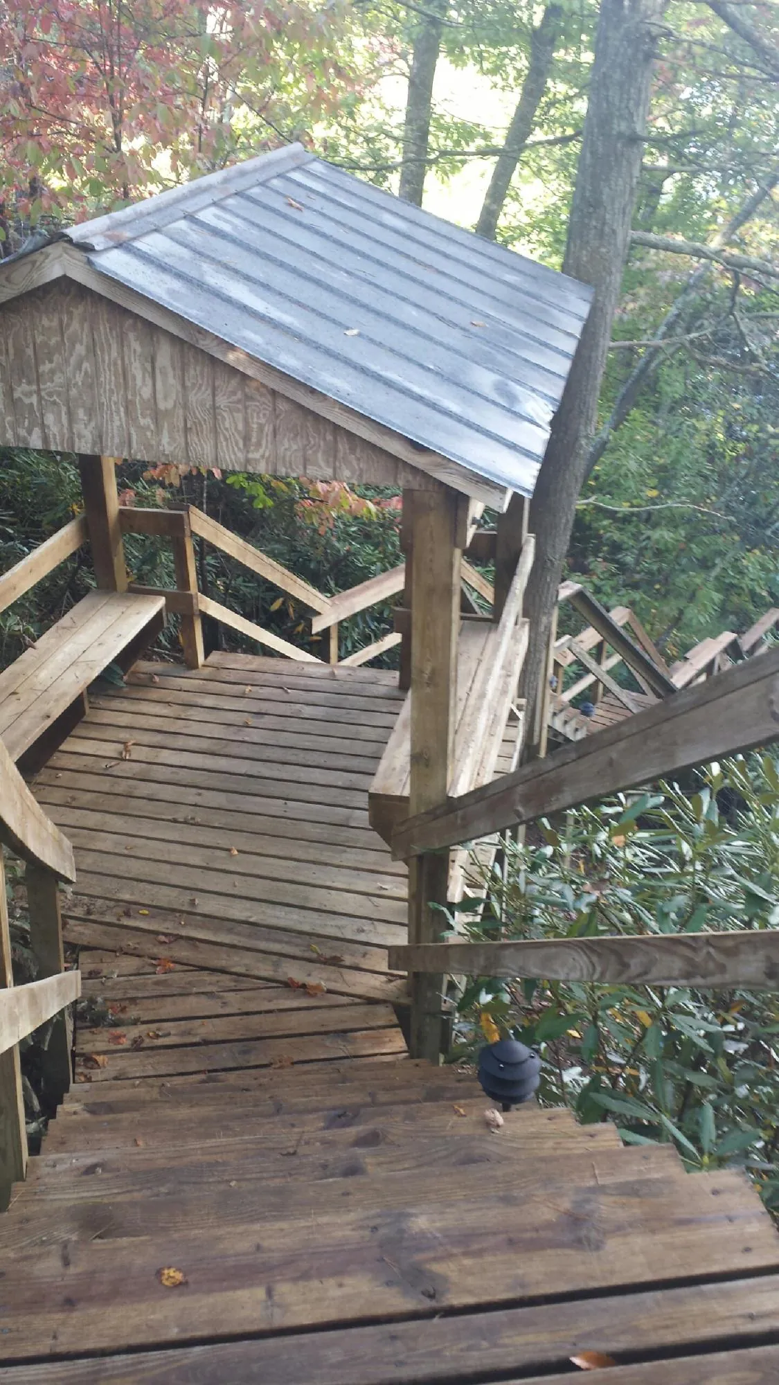 Metal roofed shelter over wooden steps on a wooded walkway — Skylight Repair & Installation work by our crew in Mandan