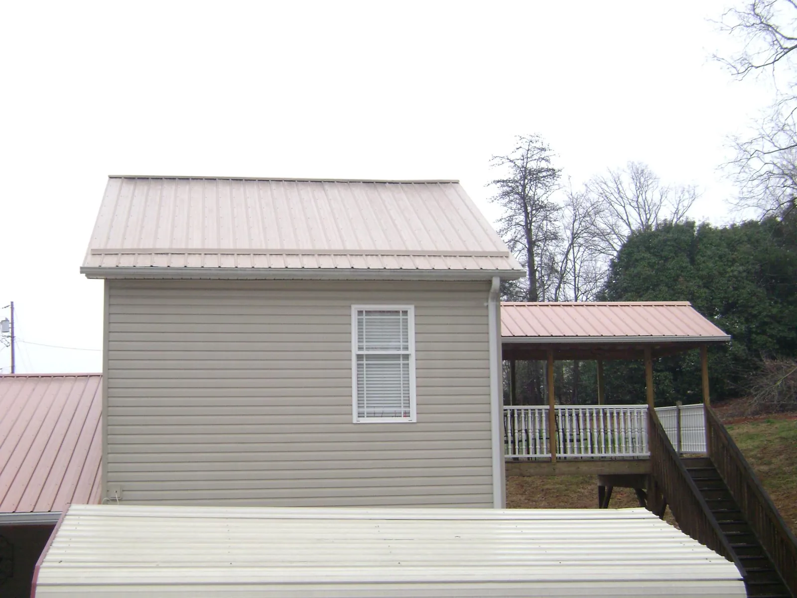 Tan metal roofs on a two story addition and attached porch, from a Roof Replacement job in Mandan